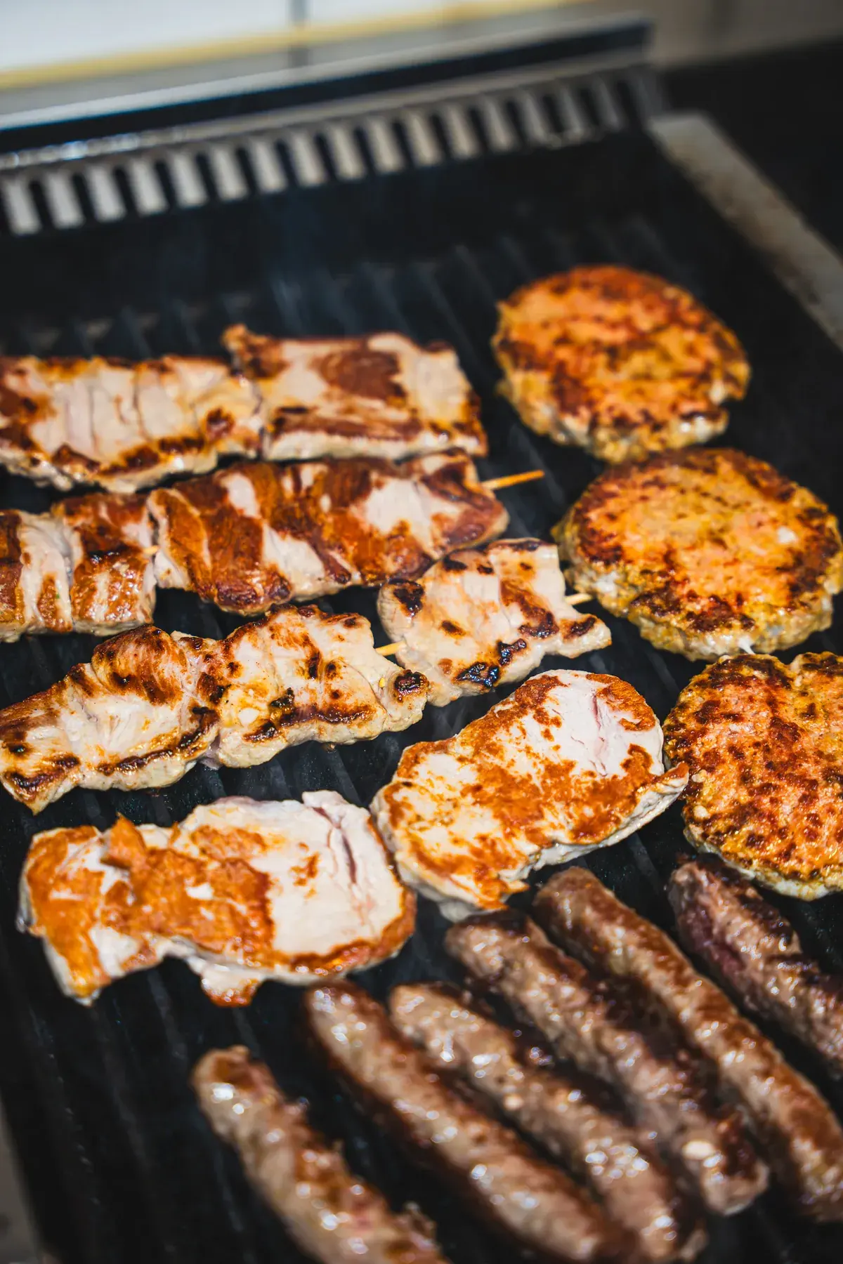 Grillrost voller Fleisch, Cevapcici und Hacksteaks