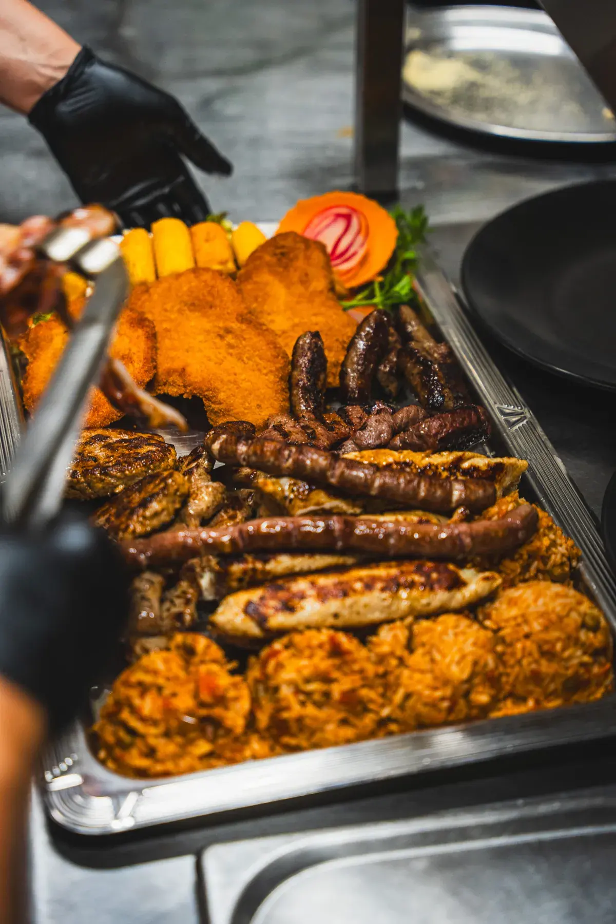 Grillplatte mit Cevapcici, Fleisch, Schnitzel und Djuwetschreis in der Küche