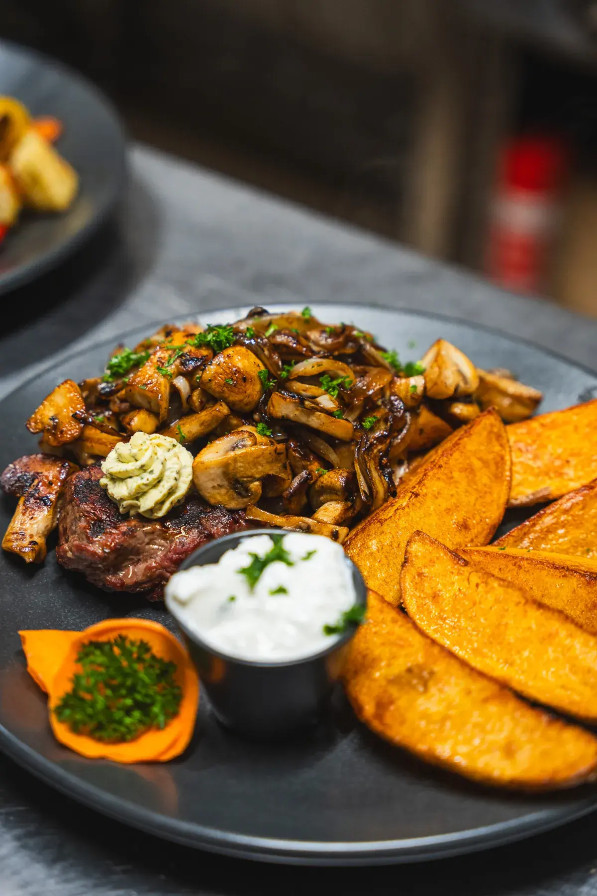 Rumpsteak mit Champignons, Kräuterbutter, Kartoffelspalten und Sour Cream